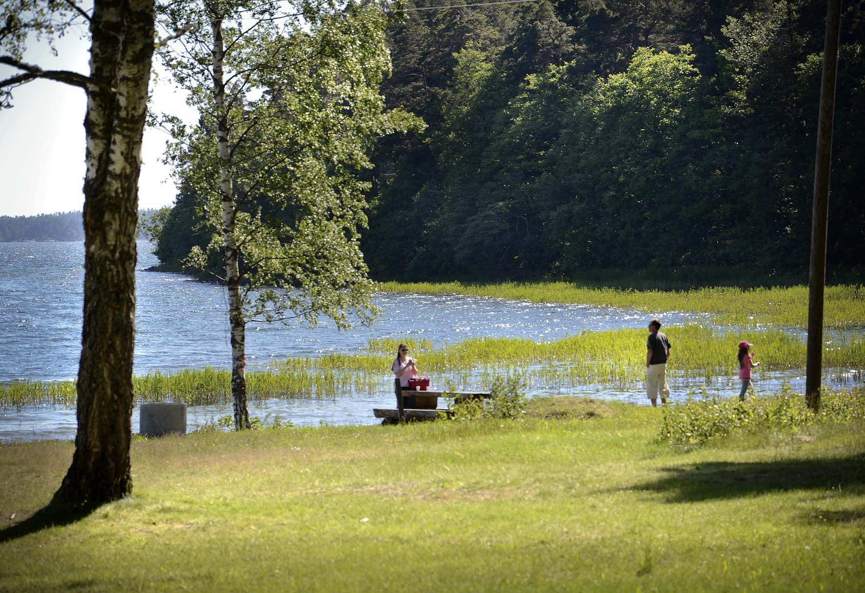 En familj vid ett picknickbord vid vattnet.