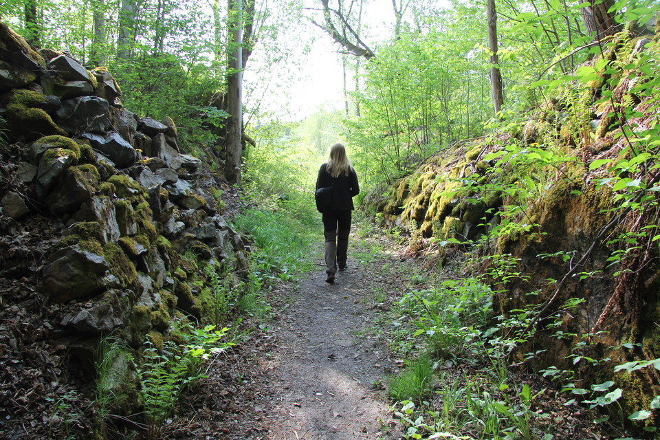 En person går på en stig mellan stenpartier.