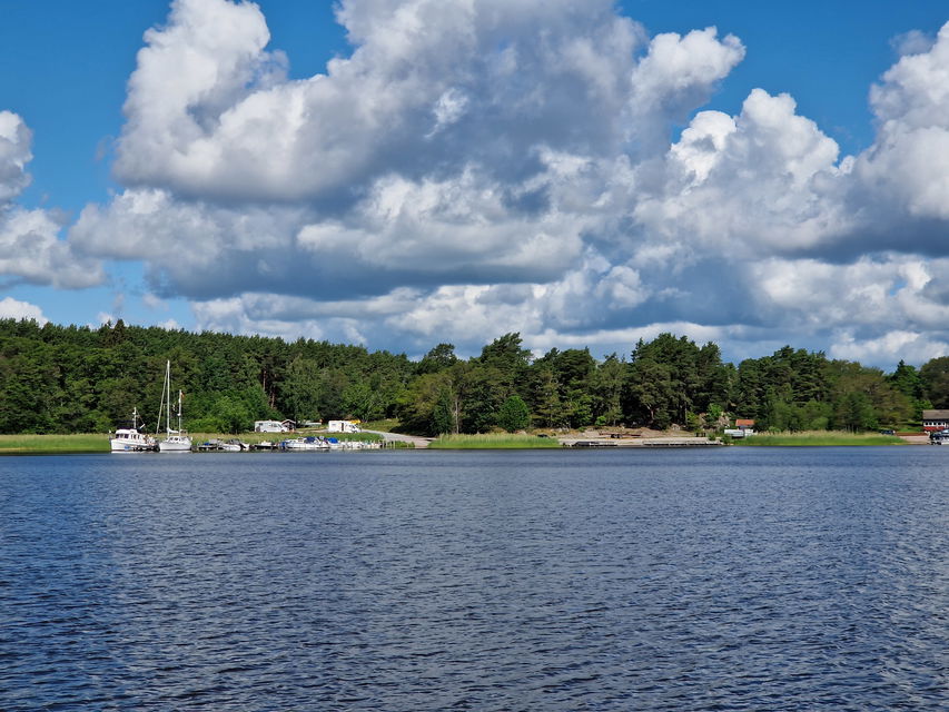 Vy in mot ö och gästhamn. Några båtar ligger vid bryggan.