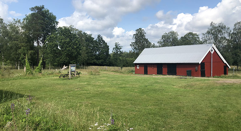 röd stuga med en informationsskylt vid sidan samt bord och stolar att sitta vid