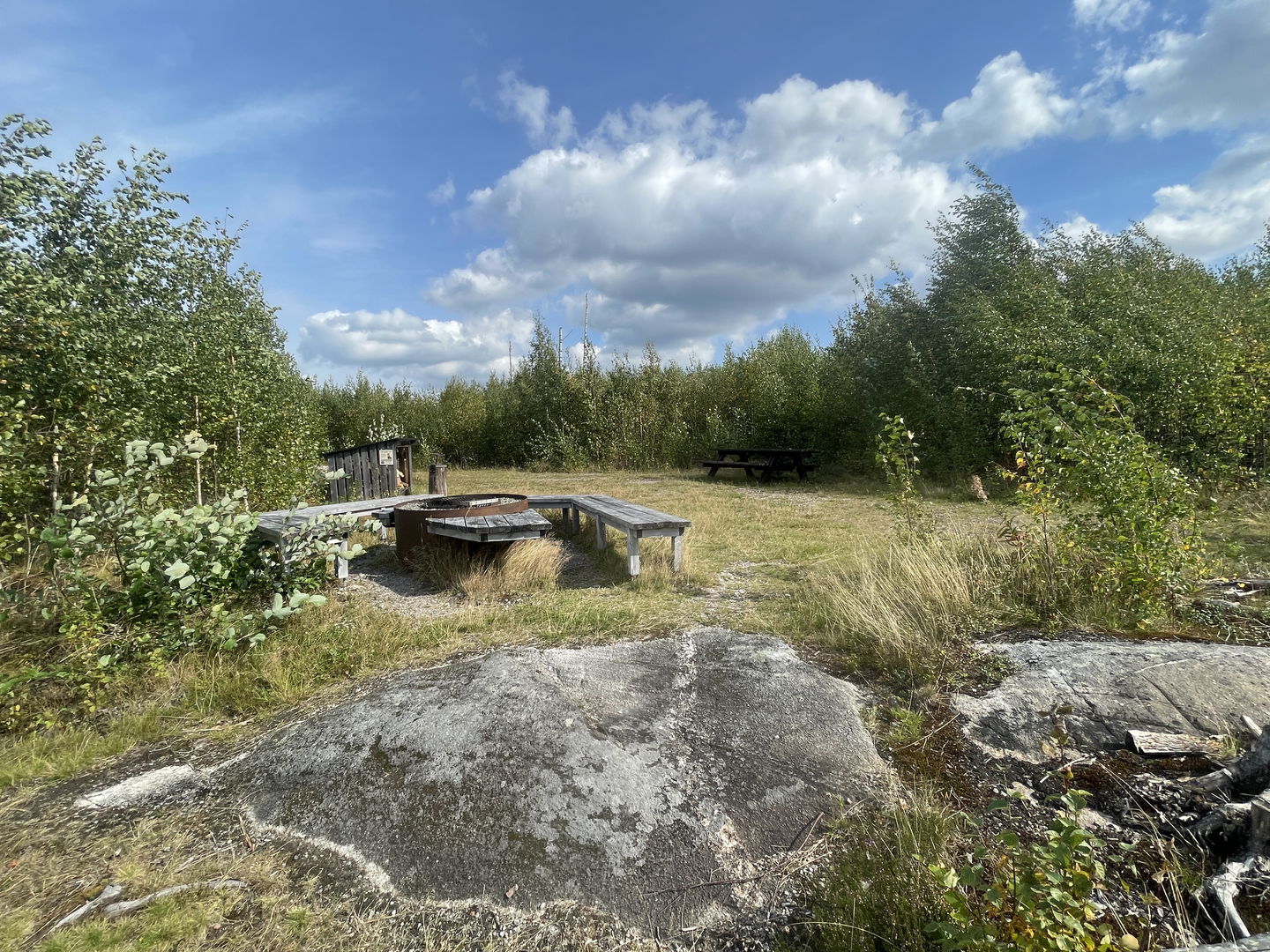 Rastplats med picknickbänk, eldstad och vedförråd.