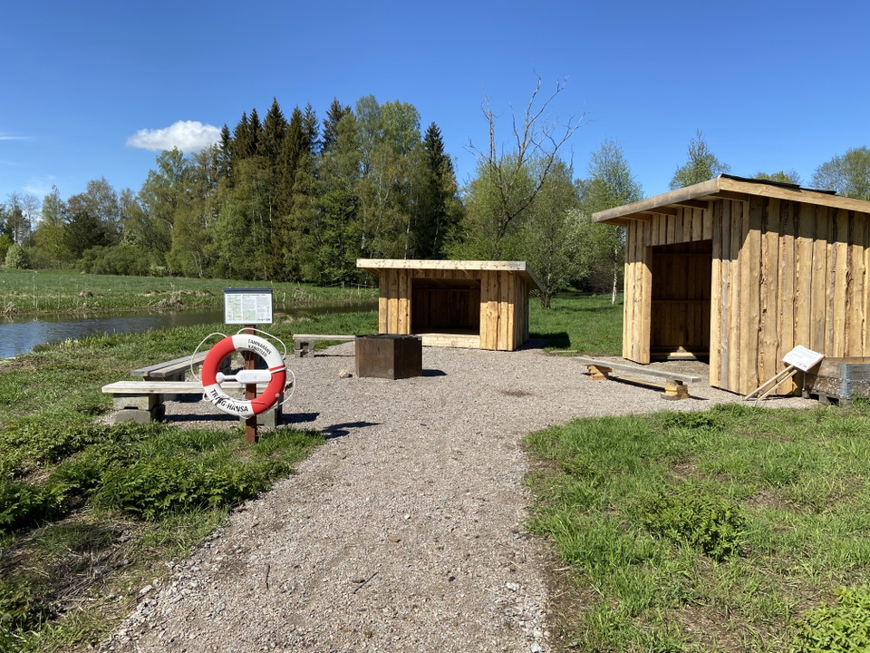 Två vindskydd nära Tämnarån och framför en eldstad med sittbänkar runt.