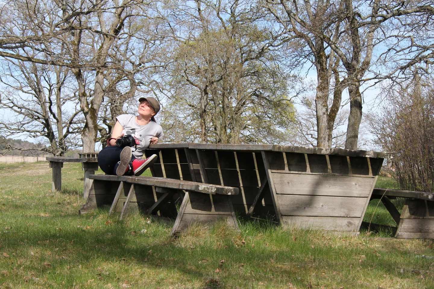 En person sitter på en bänk vid ett bord och njuter av solen.