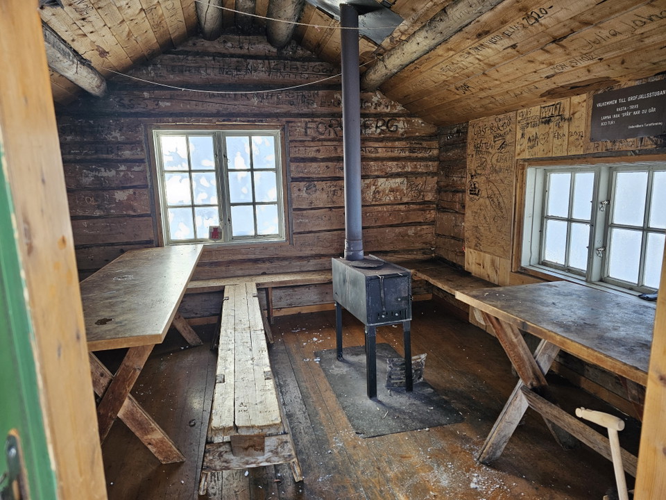 En raststuga med bord och bänkar samt en kamin i.