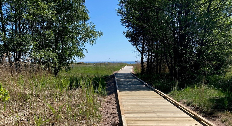 Tillgänglighetsanpassad spång till strandnära rastplats med eldstad.