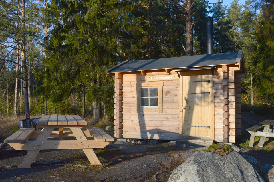 En liten stuga med två bänkbord utanför