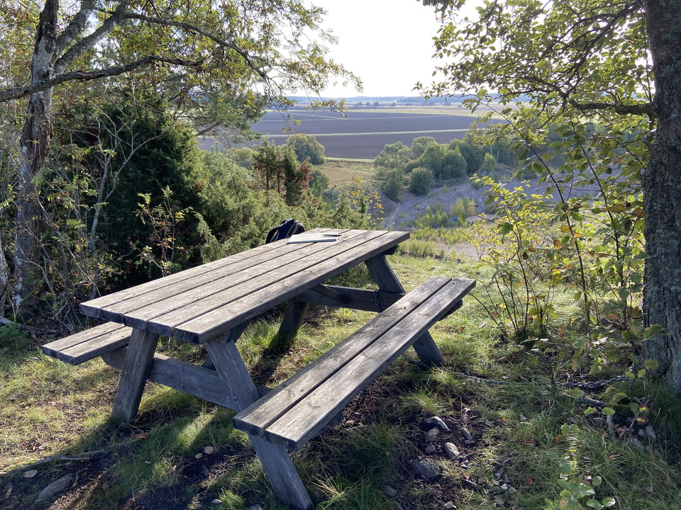 Ett bänkbord står uppe på en höjd. Från rastplatsen har man utsikt över en djup grusgrop.