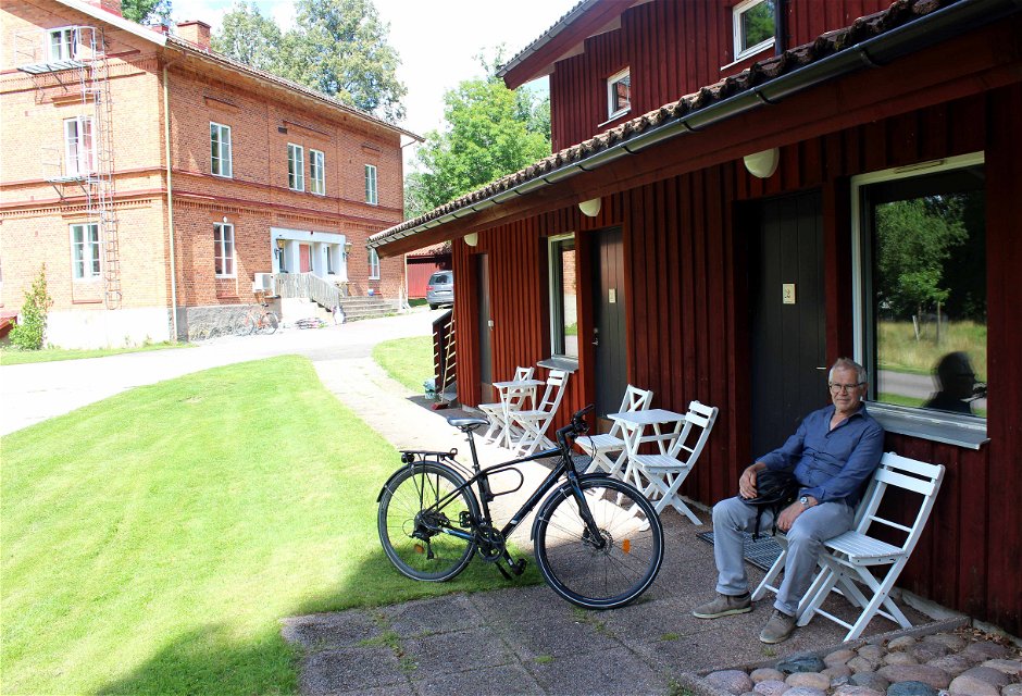 En man vilar på en bänk med en cykel bredvid sig, utanför boendet vid Kungskvarnen i Borgvik