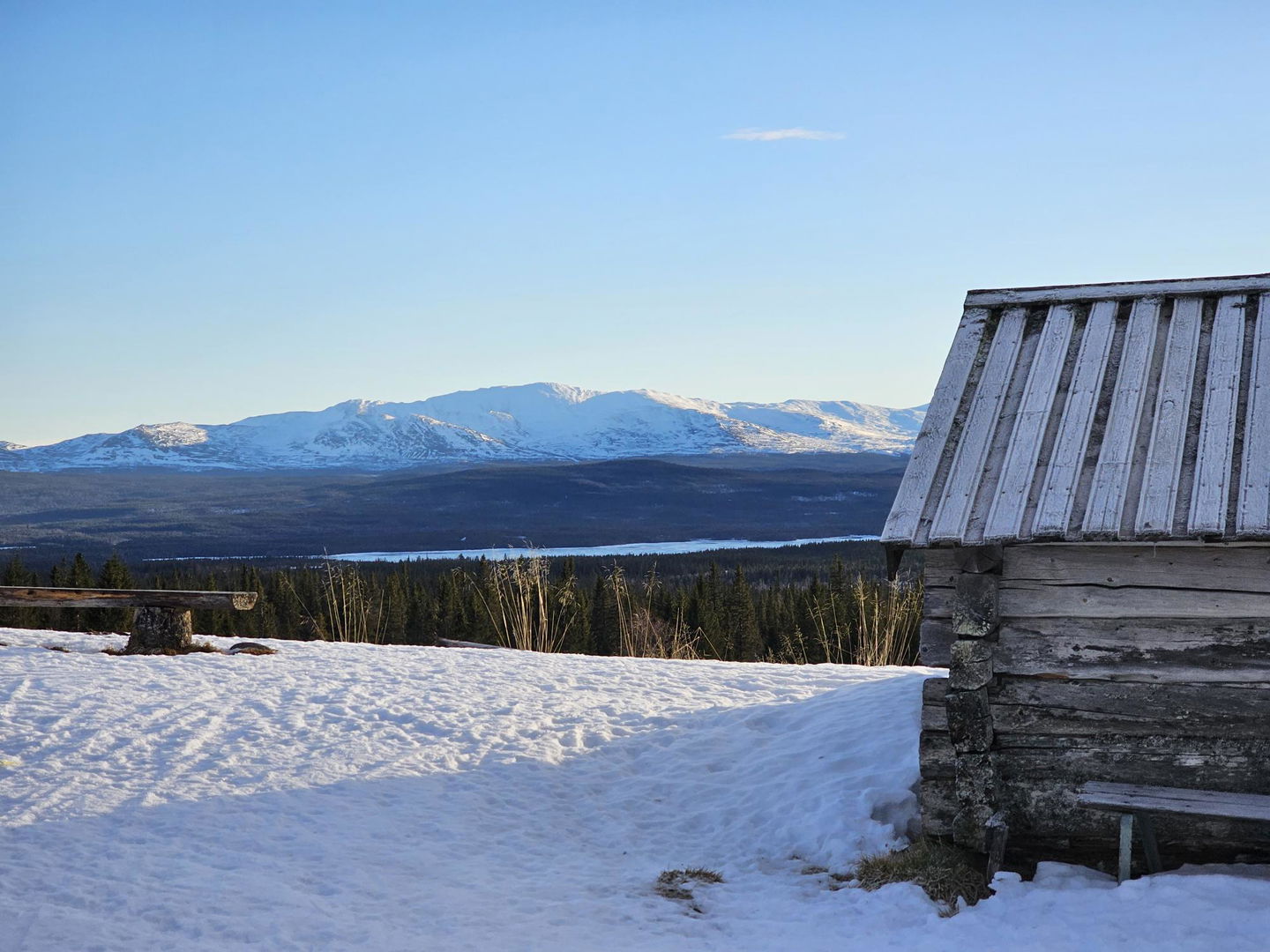 Utsikt mot ett fjäll med en fäbod i framkanten 