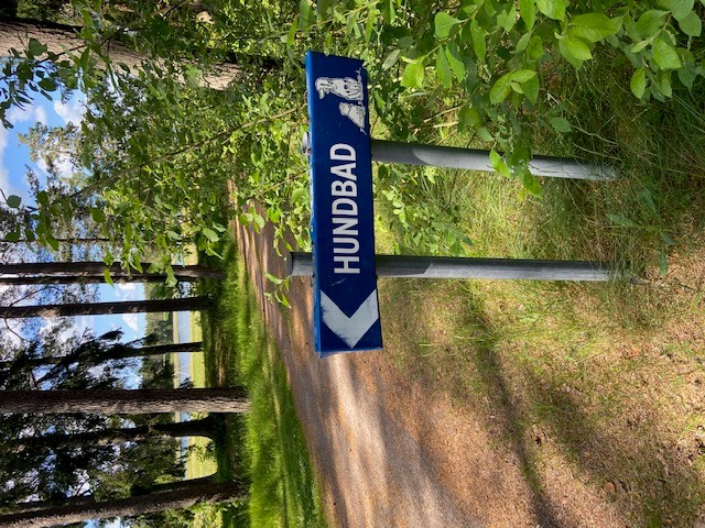 Skylt med pil till vänster mot hundbadplatsen