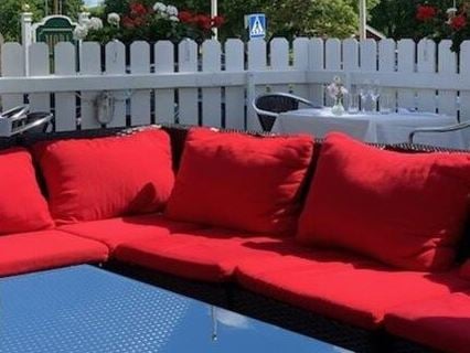 En röd soffa med ett bord och ett vitt staket.