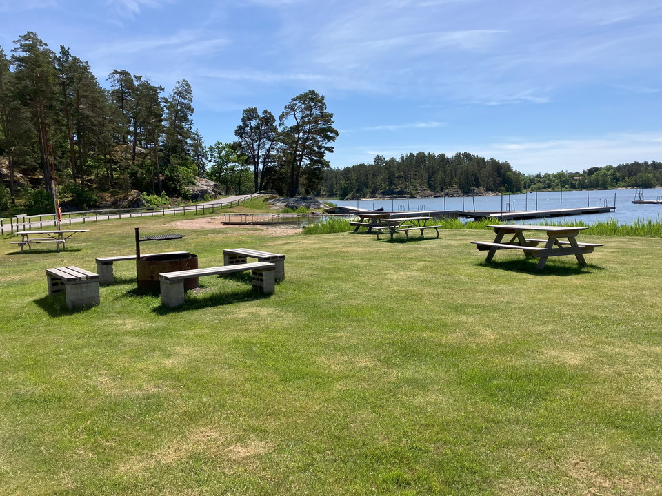Sandgärdets badplats med grill, bänkar, ved och toalett.