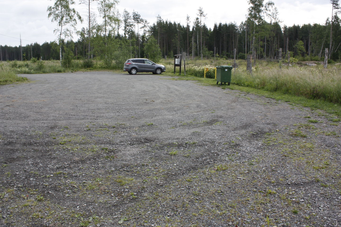 En stor grusplan med vägbom ned mot vattnet. En informationsskylt står vid parkeringens kant.