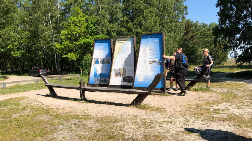 Tre segelformade informationsskyltar med två sittbänkar bildar ett skepp