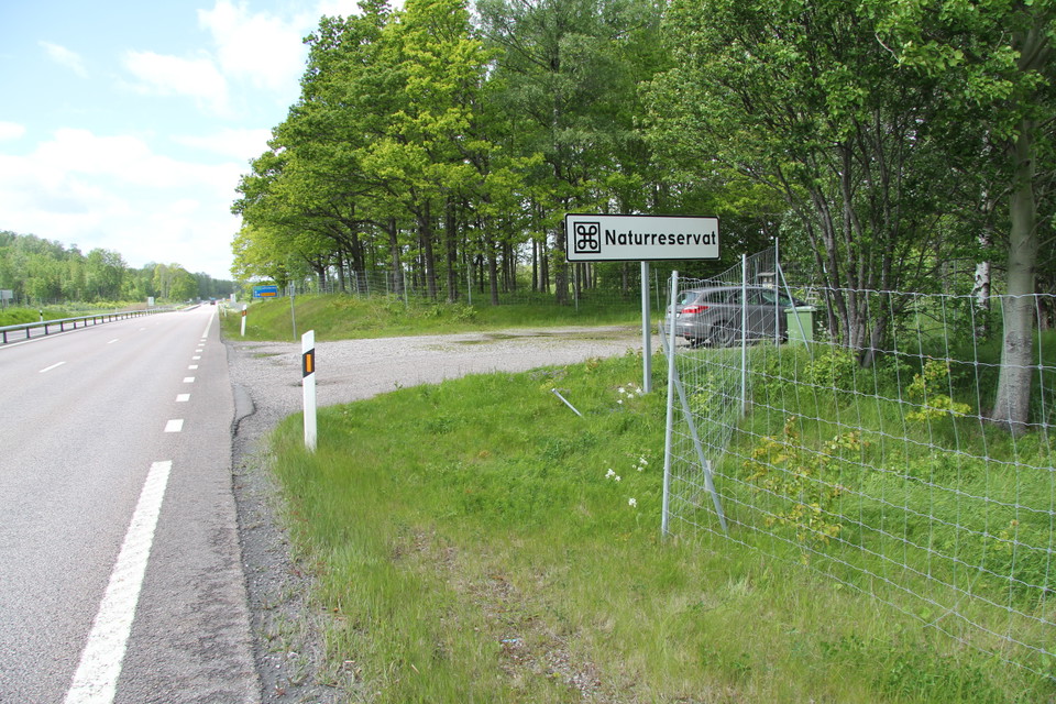 Bild från E20 där man ser skylten för naturreservat och parkeringen.