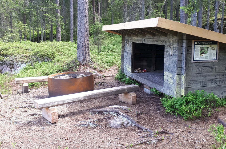 Rund grillstad med bänkar vid vindskydd.