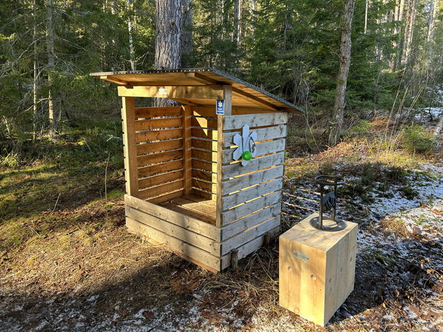 Vedförråd och huggkubbe/manuell vedklyv intill parkering, Stora Envättern