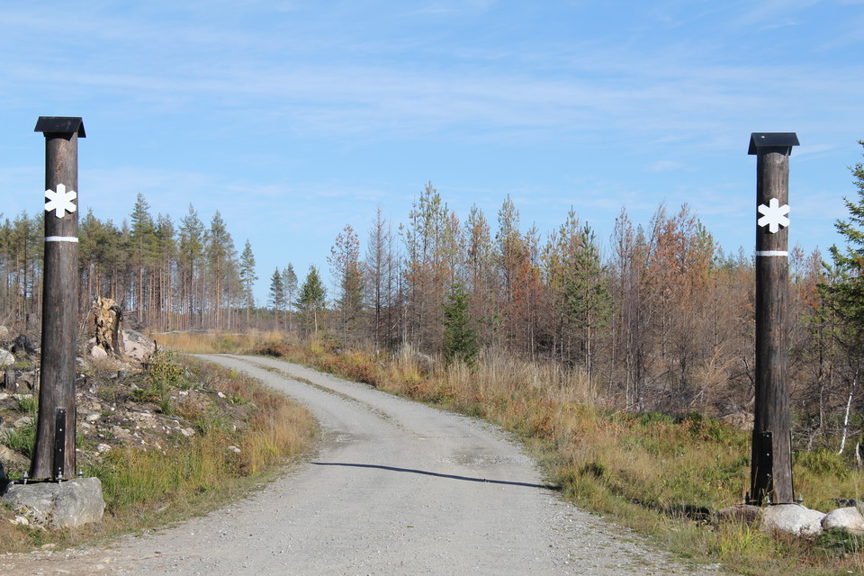 Ingången till naturreservatet. På var sida av grusvägen står två brända trädstammar med vita markeringar som visat att här är ett naturreservat.