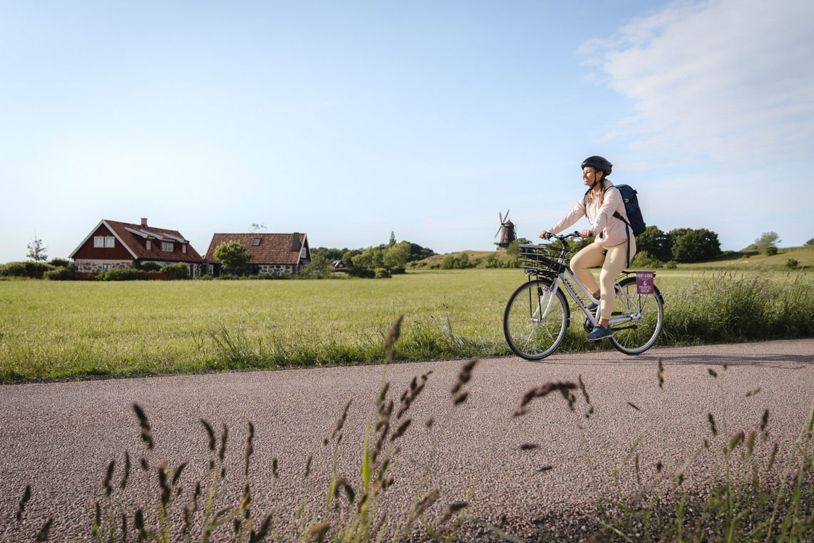 Kvinna som cyklar vid en åker.