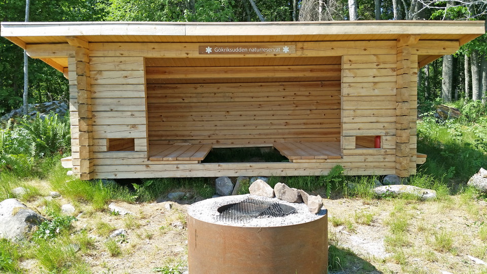 Knuttimrat vindskydd med en rund eldstad framför.