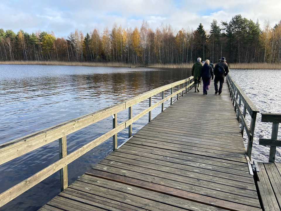 Höstbild. Vattenspegel på ena sidan av bryggan, några personer på bryggan långt bort