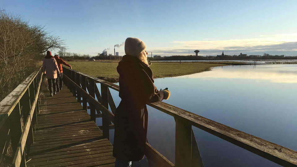 En kvinna står på en spång och blickar ut över vattnet