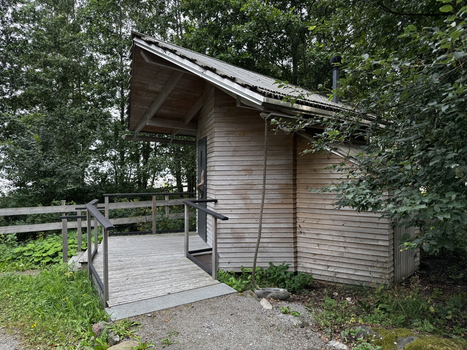 Ett litet trähus med ramp upp till dörren.