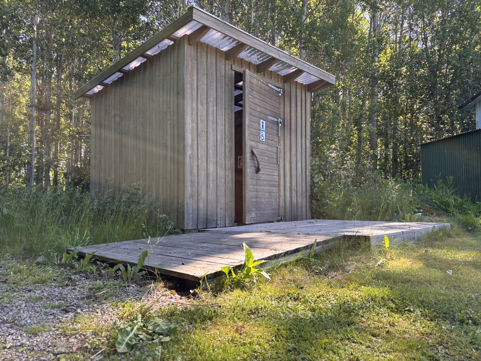 Bild på utedass med ramp som har flera glipor.