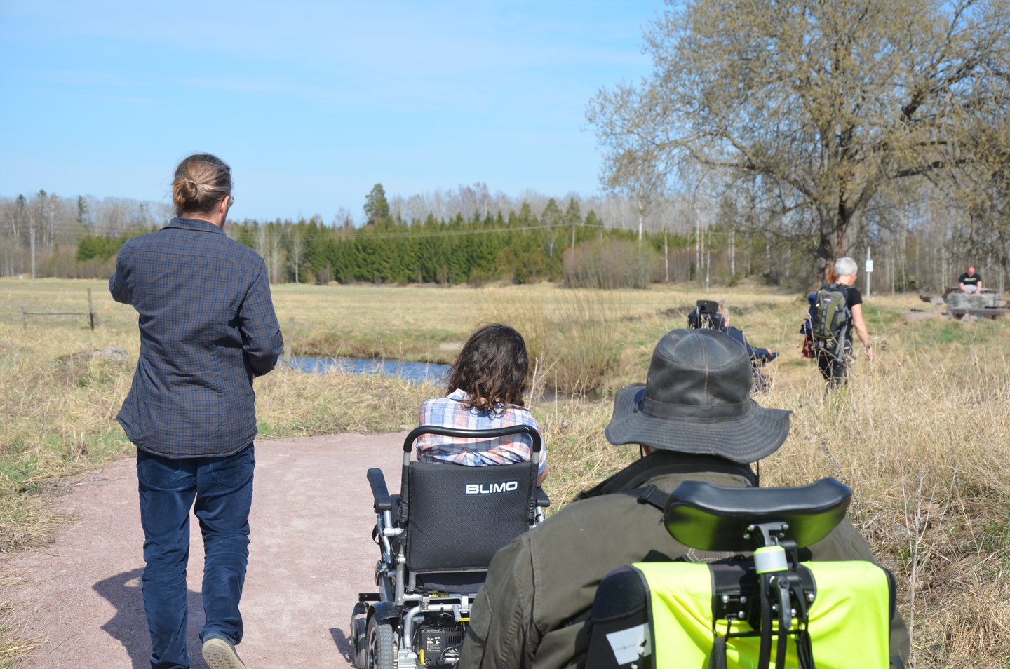 Tre personer vandrar, två av dem använder rullstol.