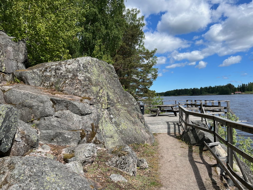 Grusad gångväg intill en klippvägg och med en sjö på andra sidan.