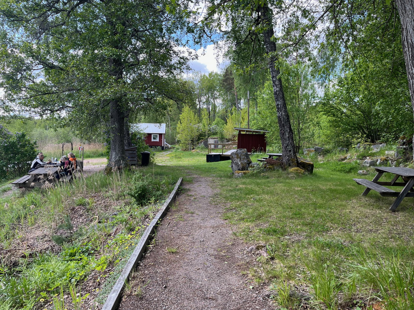 Gångväg som leder mot en rastplats med flera bänkbord.