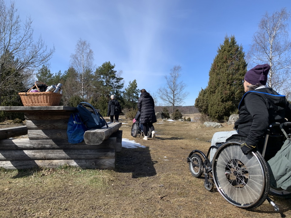 En kvinna i rullstol i en hagmark med rastbord.