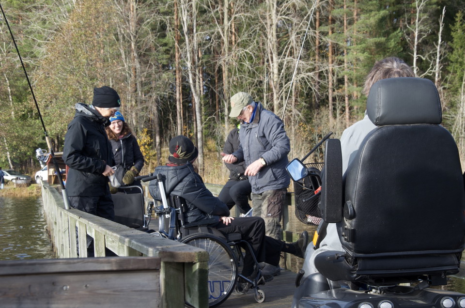 En brygga med en grupp människor som grejar med fiskespön.