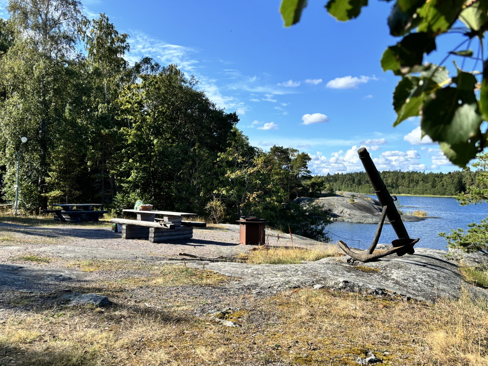 Bild på två bird och en eldstad, bredvid ett stort ankare. I bakgrunden syns havet.
