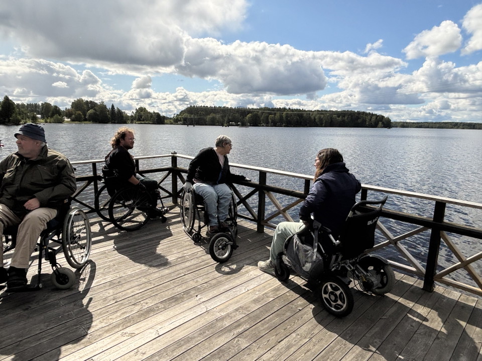 Fyra personer som använder rullstol är ute på en brygga.