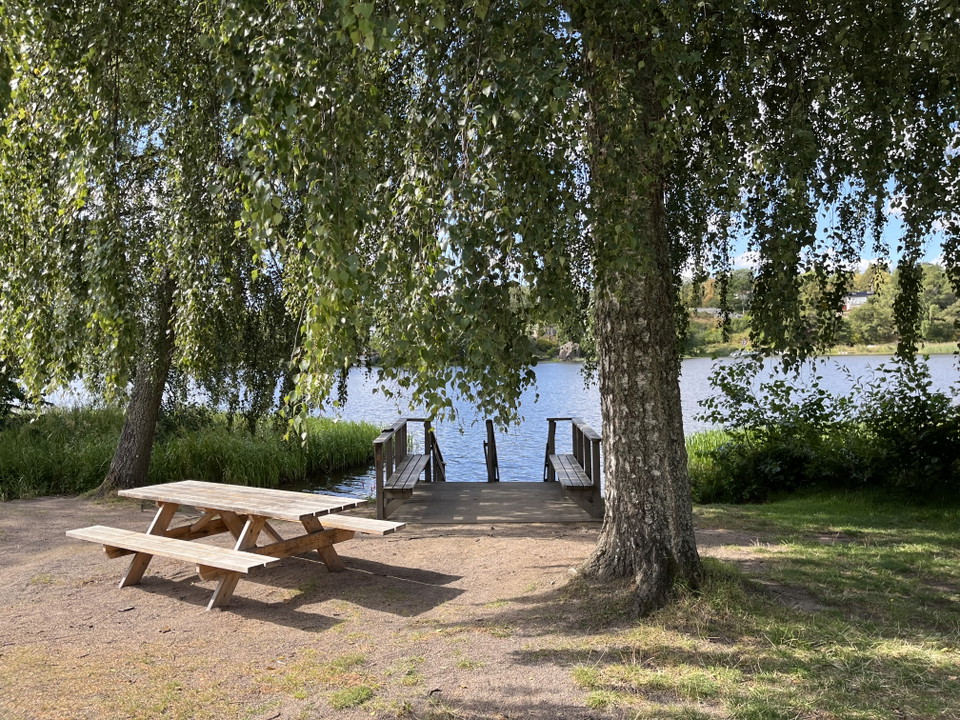 Bild visar ett rastbord vid vatten och en brygga.