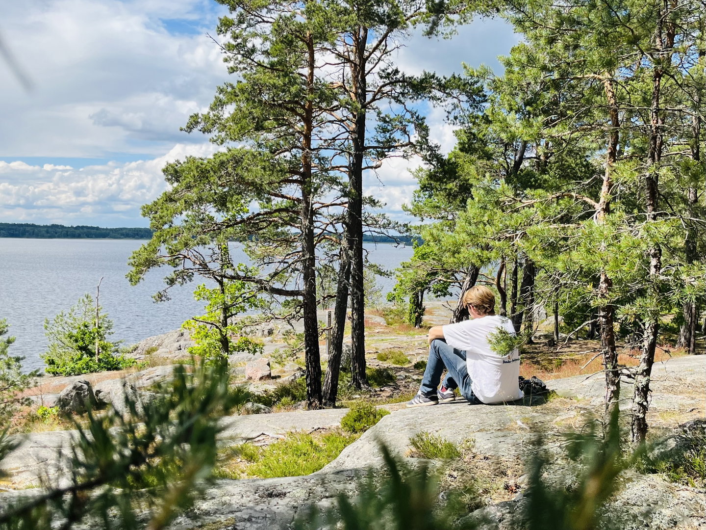 En person sitter på en klippa och tittar ut över vattnet. 