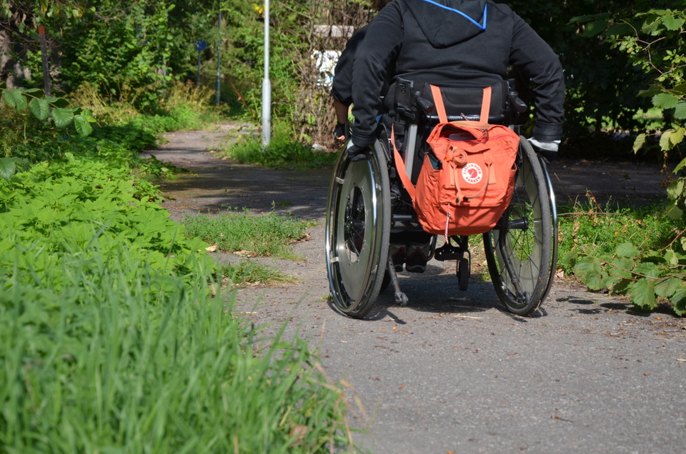 Bred, grusad väg med rullstolsanvändare. 