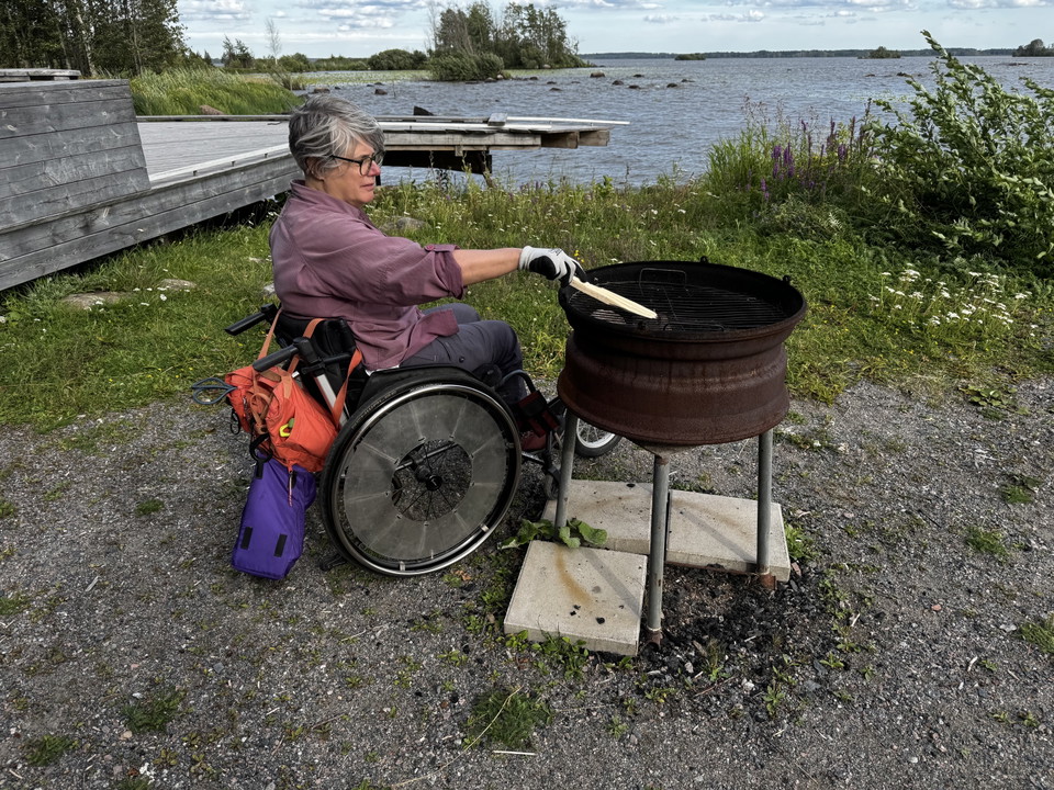 En kvinna i rullstol vid en grill.