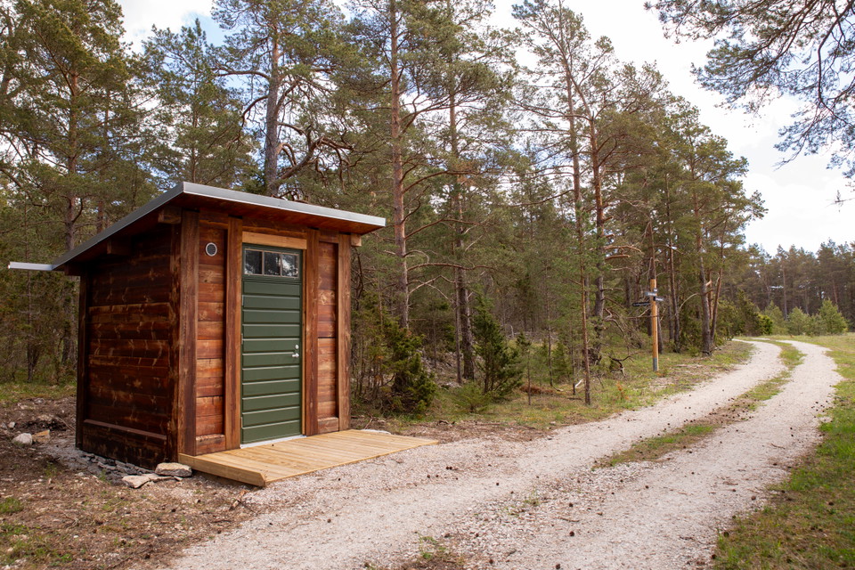 Mindre trähus i anslutning till grusväg.