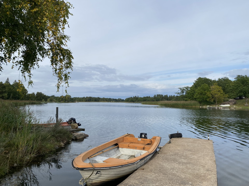 Hästenäs - Stenbrygga med båt på blankt vatten