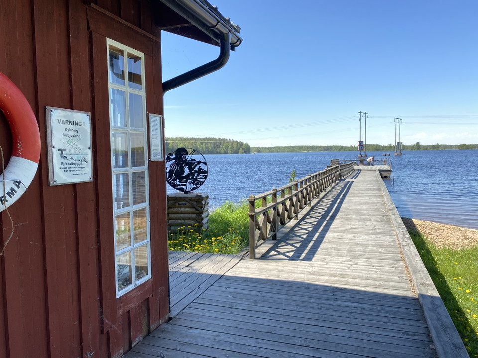 Ett rött hus, brygga ut i vattnet.