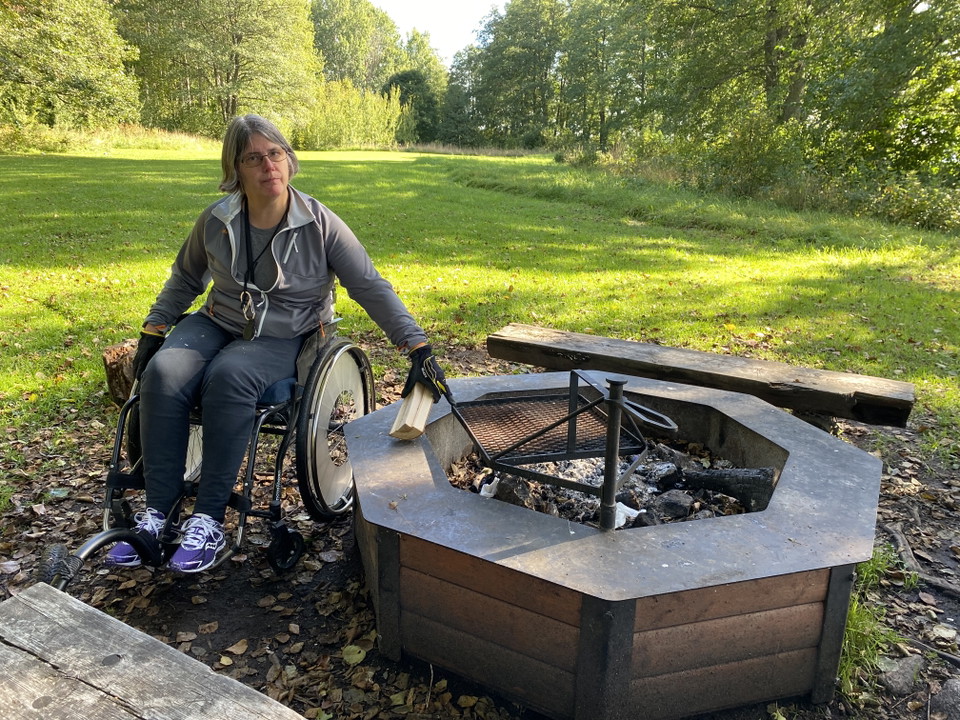 En kvinna i rullstol vid en eldstad.