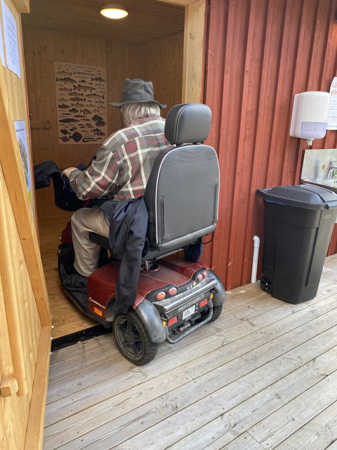 En man i permobil kör in till torrtoaletten.