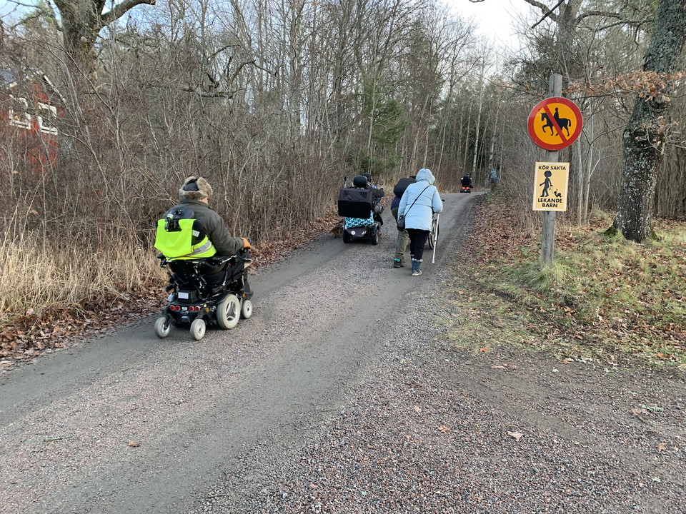 Grupp med personer i rullstol påväg uppför en kort men brant backe.