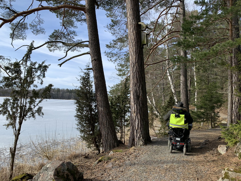 Man i rullstol åker på stig vid sjö