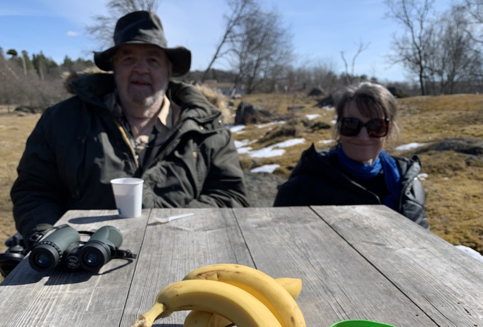 Två personer fikar vid rastbord utomhus