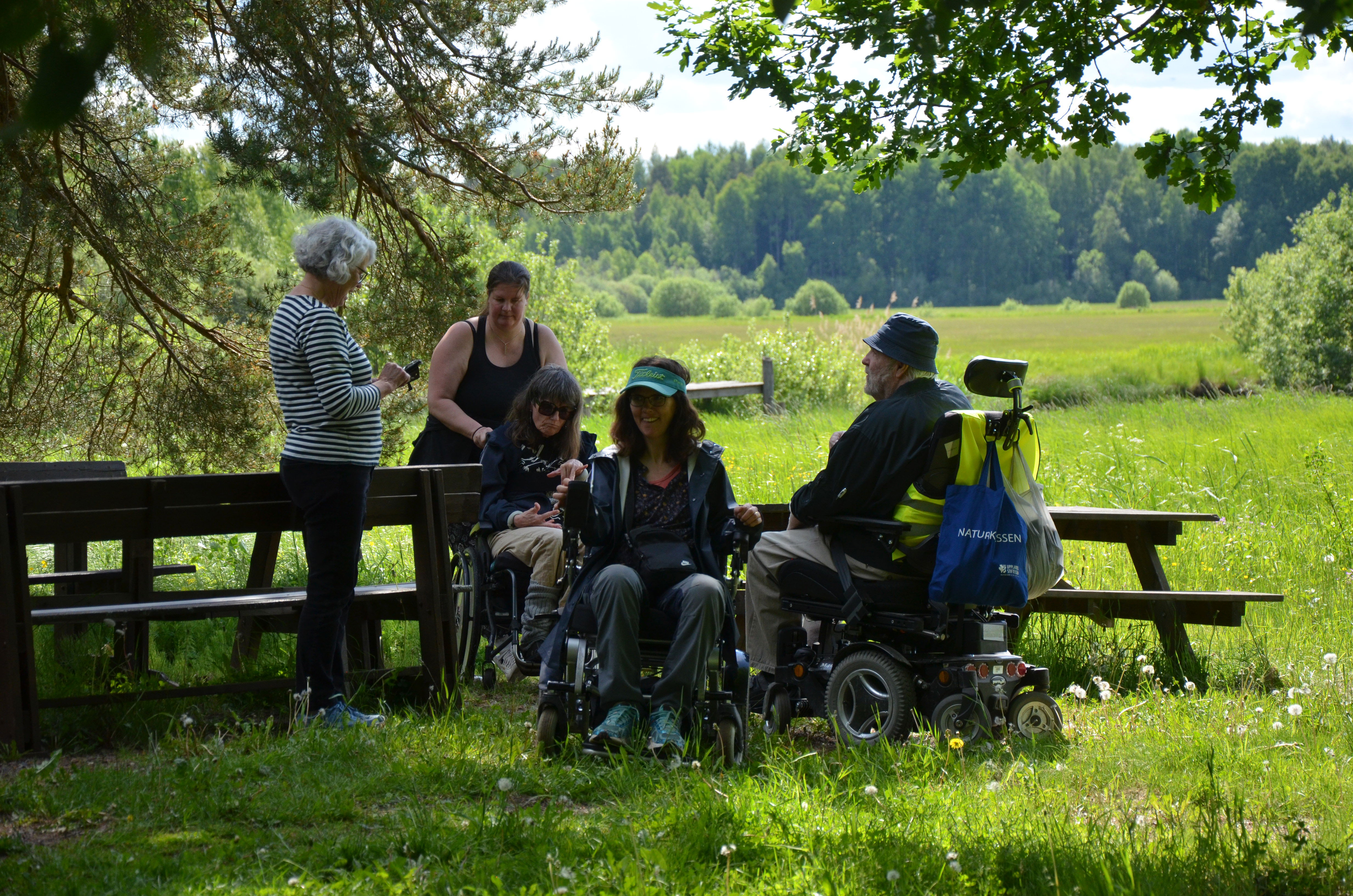 Grupp med personer i rullstol vid rastbord